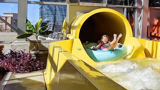 Girl exiting yellow water-slide at Water-Zoo Indoor Water Park in Clinton, Oklahoma